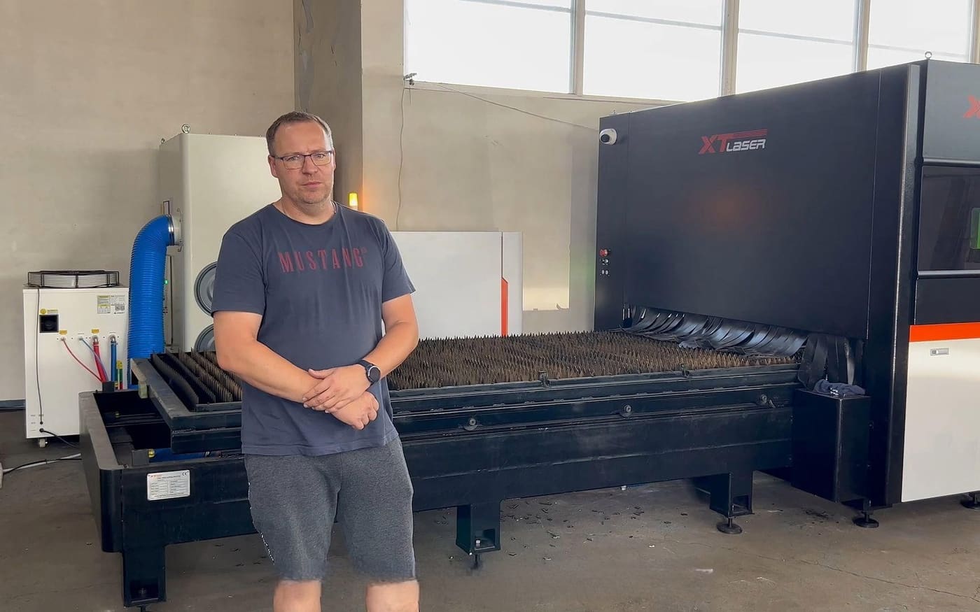 A visitor standing in front of a fiber laser cutting machine on the workshop floor.